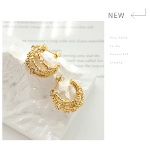 Detailed macro view of gold-plated twisted rope hoop earrings with zircon stones