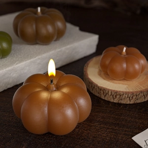 Pumpkin scented candle decor with autumn textures and burning wick in stylish warm setting