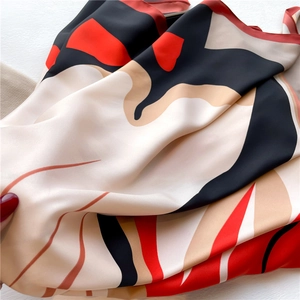 Close-up of luxury silk scarf with red and black abstract geometric pattern texture