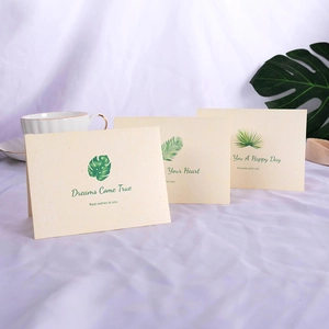 Three ivory greeting cards with green leaf prints and motivational English quotes on linen