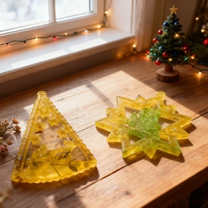 Christmas tree and snowflake resin pendant ornaments with dried flowers on a wooden sill
