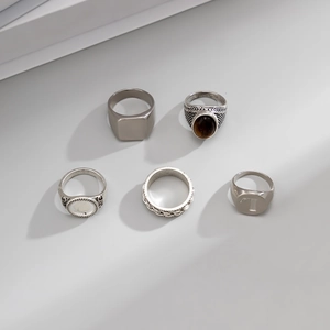 Detailed view of a 5-piece silver alloy ring set with brown gemstone and T-letter engraving