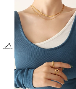 Detail of layered gold snake chain necklace and rings in polished stainless steel