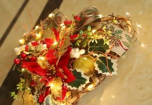 Detail of Christmas heart wreath with red poinsettia, pinecone ribbon and warm LED lights