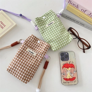 Flat lay of plaid fabric phone pouches with woven lanyards and decorative props