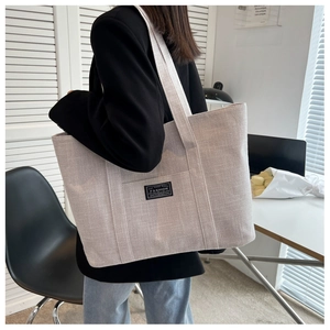 Close-up of oatmeal canvas tote bag with fashion tag and wide shoulder strap