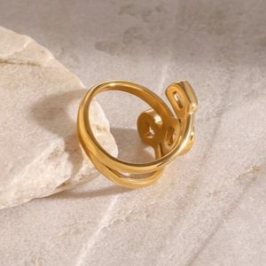Elegant gold-tone double-layered interwoven open ring on a textured stone background