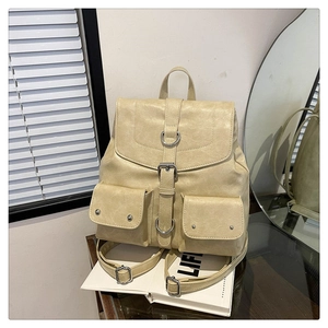Detail view of cream vintage backpack featuring dual front pockets and metal buckles
