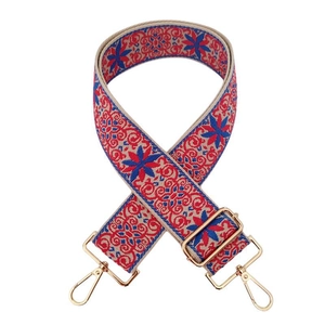Detail of ethnic embroidered bag strap with red-blue floral pattern and gold metal hooks