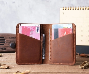 Close-up of vintage brown leather card holder with hand-stitched edges on wooden desk