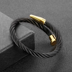 Macro shot of two-tone black and gold cable nail cuff bracelet on dark gift box