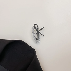 Detail of silver beaded hair clip with a black silk bow against a minimalist background