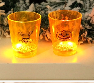 Macro detail of Halloween LED shot glasses with skull and pumpkin patterns and orange glow