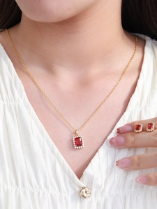 Close-up of elegant gold jewelry set with red rectangular gemstones worn by a model
