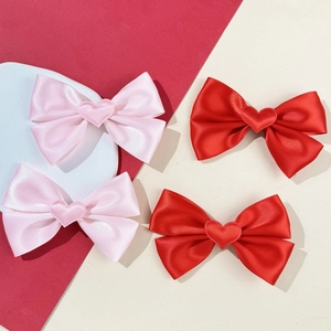 Lot de quatre barrettes nœuds en satin rouge et rose avec cœur sur plateau décoratif