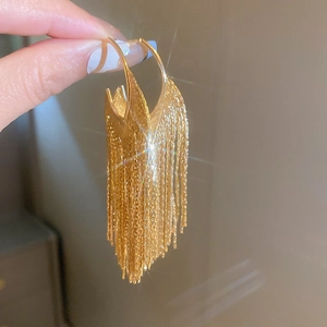 Gros plan de boucles d'oreilles dorées à pampilles avec fines chaînes métalliques