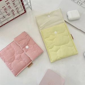 Close-up of quilted cotton sanitary napkin pouches in soft pink and yellow on a desk
