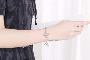 Close-up of a silver cross bracelet with pavé stones and a toggle clasp on wrist