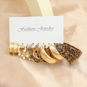 Golden earrings set with pearls and leopard resin hoops displayed on a card