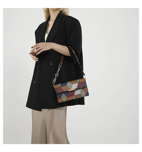 Model wearing a vintage square bag with snake texture and chain strap over a blazer