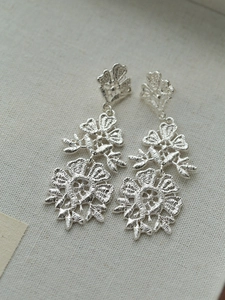 Detail of silver vintage hollow floral tassel earrings with intricate lace-like texture