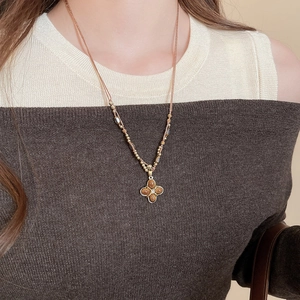 Detailed view of tiger eye stone flower pendant on woven cord necklace on model