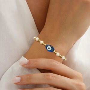 Retro freshwater pearl bracelet with 18K gold beads and blue evil eye charm on wrist