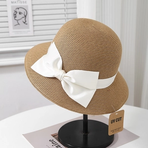 Détail d'un chapeau de paille élégant avec nœud blanc et étiquette anti-UV sur socle