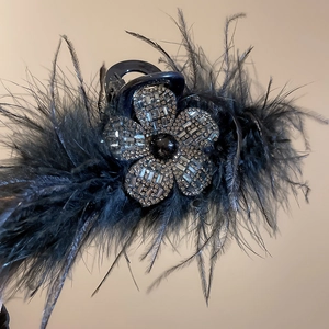 Détail de la fleur en strass et des plumes noires sur cette pince à cheveux de luxe