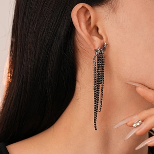 Close-up of black star tassel earrings with rhinestones worn by a model