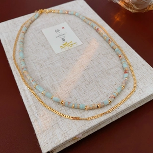 Detail of layered ethnic beaded necklace with gold chain and marble style stones