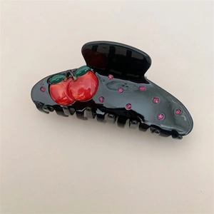 Detail of 3D red cherry accents and pink rhinestones on a glossy black hair claw clip