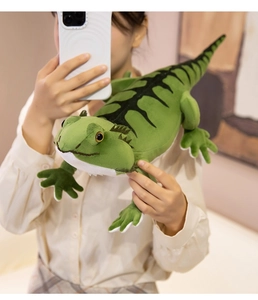 Detail of green plush lizard toy with black stripes held by a person in a home setting