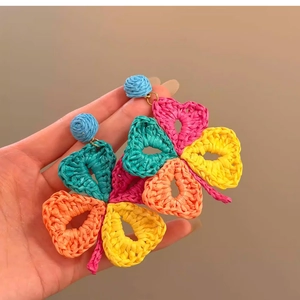 Detail view of woven raffia flower earrings showing colorful bohemian texture and design