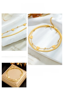 Close-up of double-layer gold anklet with heart pendant and sleek snake chain link