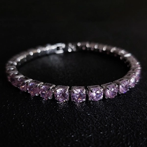 Macro detail of silver tennis bracelet with round cut pink zircons on black leather