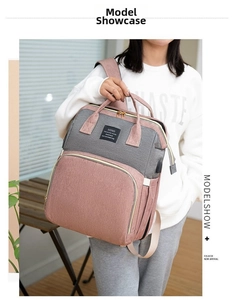 Detailed view of grey and pink waterproof mommy backpack worn by a model in a bright setting
