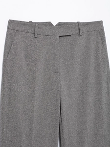 Detailed macro view of gray herringbone suit trousers showing the waist and pockets
