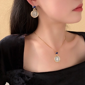 Detail of elegant gold and silver coin pendant necklace and earrings set with blue gems
