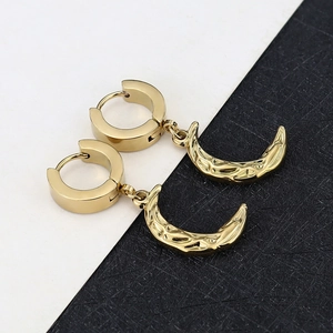 Polished gold crescent moon dangle earrings featuring textured metal on dark leather backdrop