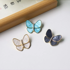 Detailed view of elegant butterfly brooches in blue, white and grey with pearl accents
