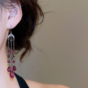 Gros plan de boucles d'oreilles à pompons avec cristaux violets et crochet argenté