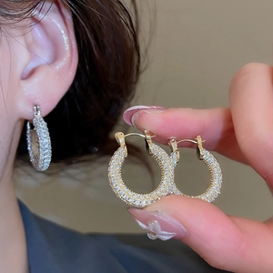 Close-up of gold-plated U-shaped huggie earrings with shimmering pavé zircon stones