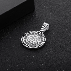 Macro shot of vintage silver stainless steel round pendant with hammered texture and beaded edge