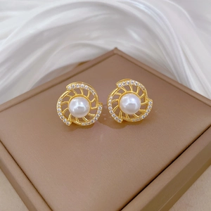 Close-up of luxury rotating pearl and pavé diamond earrings on brown jewelry box