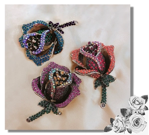 Detailed view of three vintage rose brooches with colorful rhinestones on silk