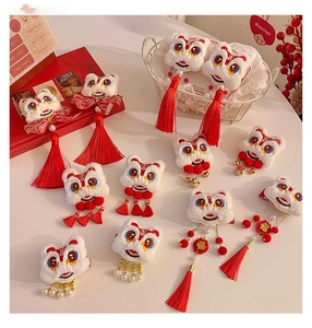 Detailed close-up of lion dance plush hair clips with red tassels and gold Fu embroidery