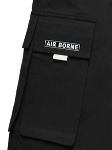 Detail der Cargo-Seitentasche mit gewebtem Air Borne Label auf schwarzem Twill-Stoff