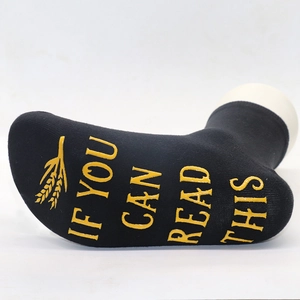 Detail of black cotton socks featuring gold non-slip lettering on the sole