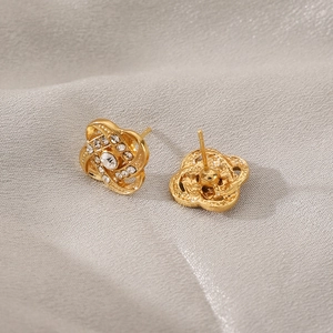 Detailed macro view of golden hollow floral earrings with embedded zircon accents